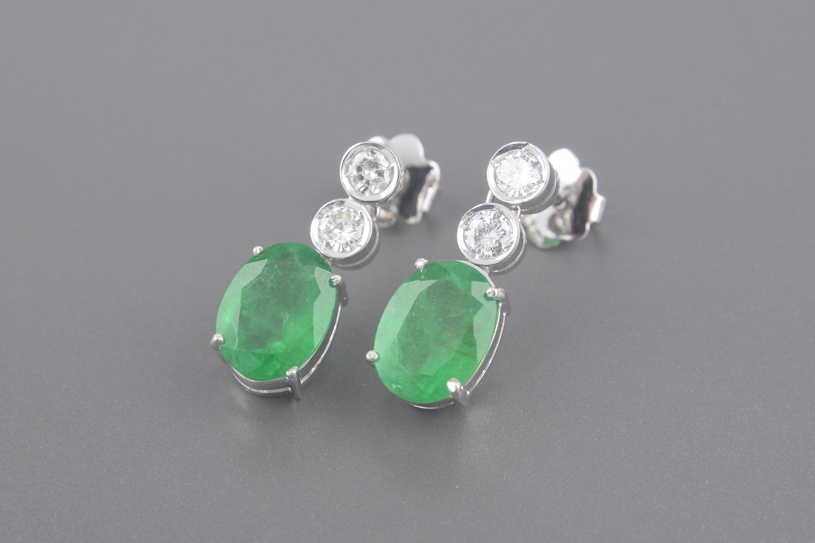 Brincos em Ouro Branco 18k com Aprox.4.75ct Esmeraldas Ovais de 10x8mm e Aprox. 60pts de Brilhantes