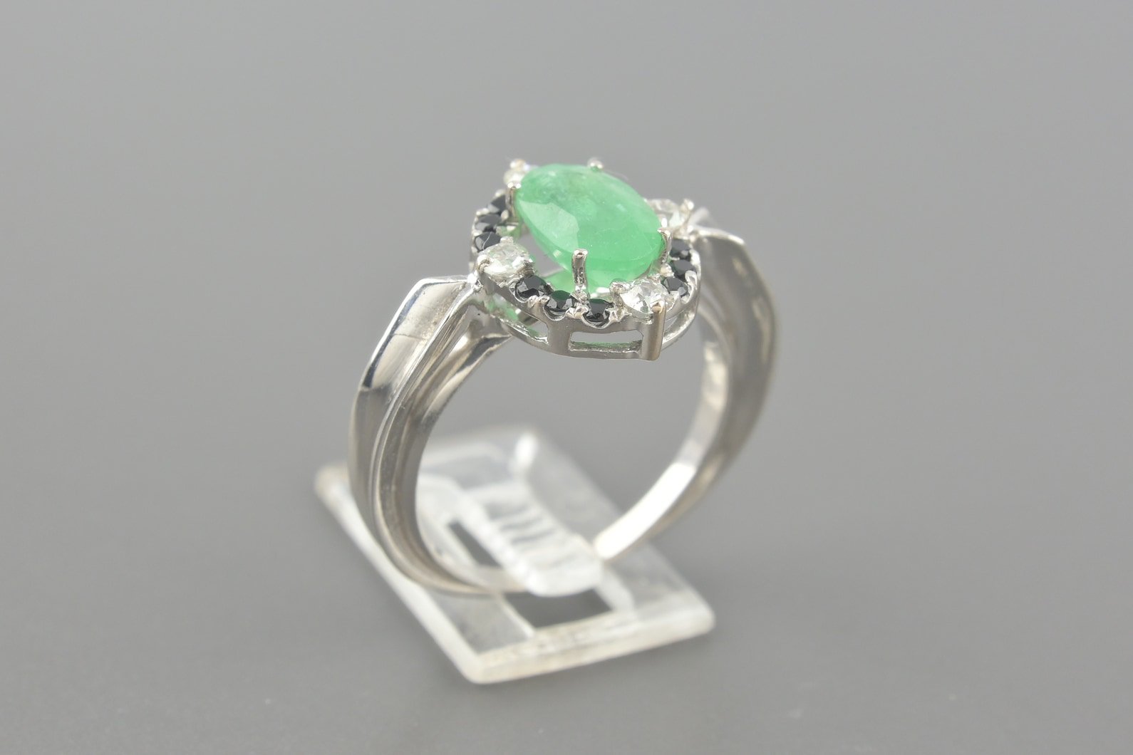Anel em Ouro Branco 18k com Esmeralda Oval de 8.6x5.9mm, Onix de 1.3mm e Aprox. 20pts de Brilhantes